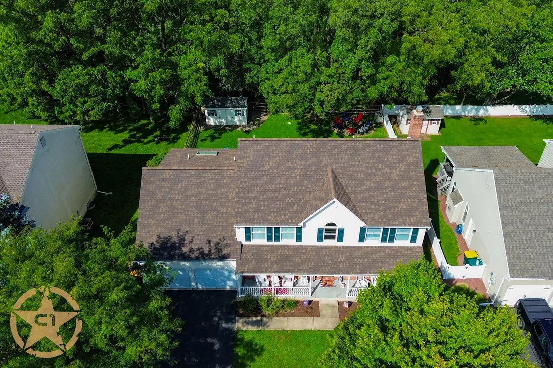 Aerial view of a completed roof replacement on a two story home surrounded by trees