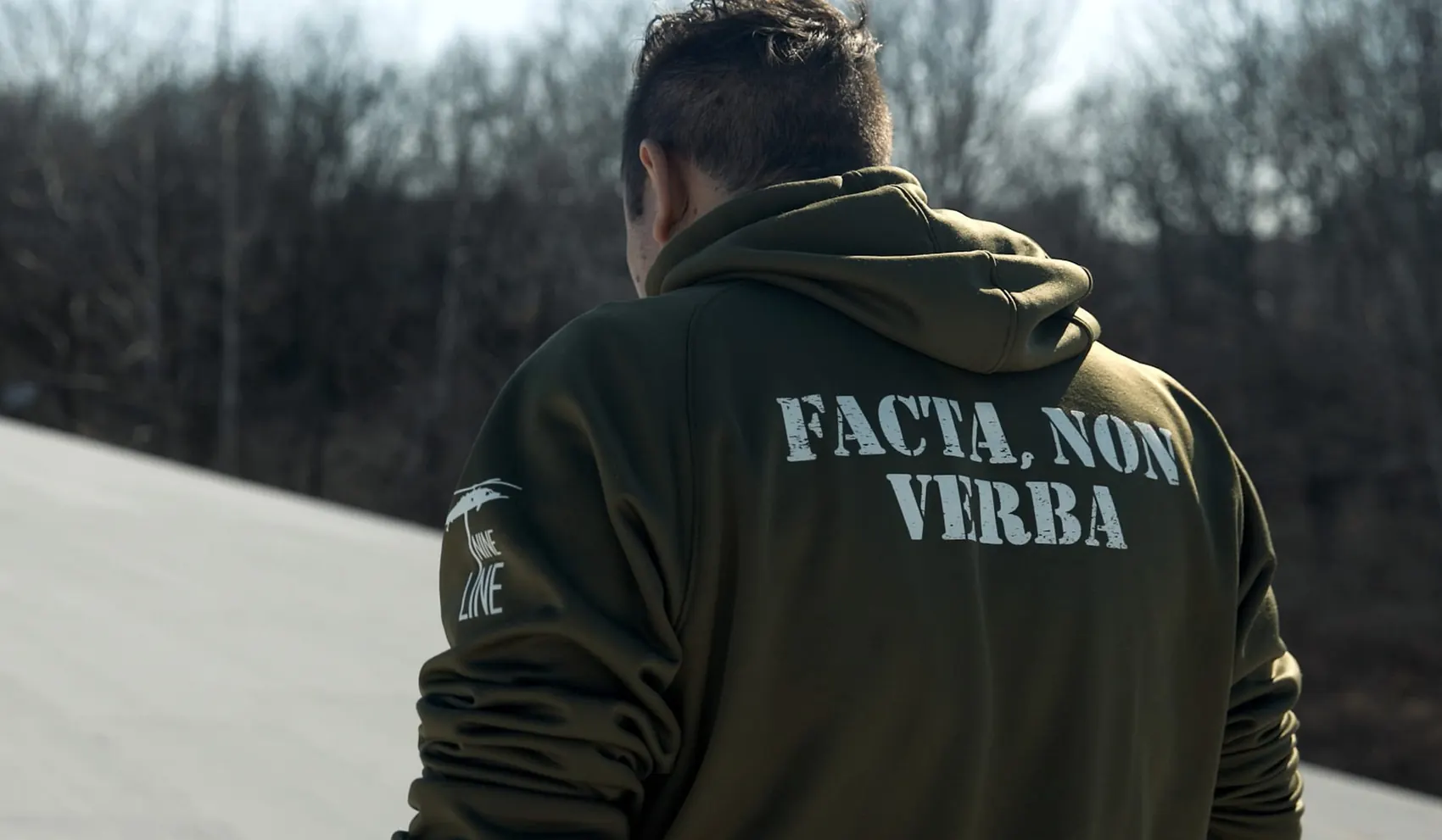 Condition One team member wearing an olive drab hoodie reading Facta Non Verba