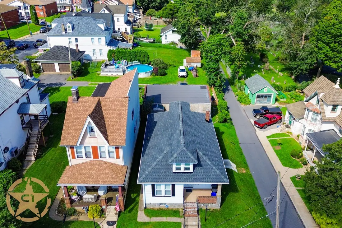 Aerial view of a completed roof replacement on an older home on a tight in town street