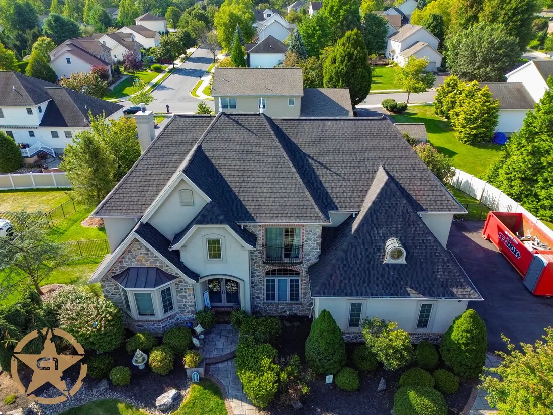 Completed roof replacement on a large stone and stucco home with a steep pitch