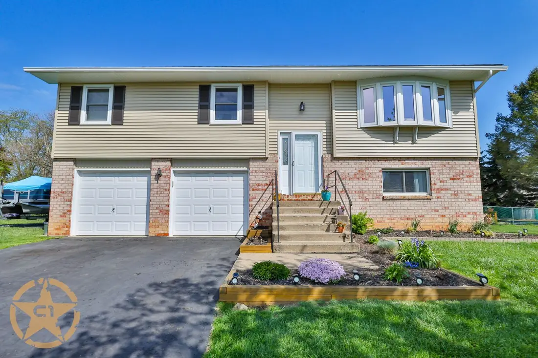 Completed siding on a split level home with white garage doors